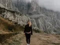 Kobieta na tle majestatycznych gór w Val di Funes. Mgła otula szczyty, tworząc mistyczną atmosferę.
