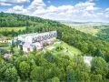 Hotel w otoczeniu zielonych lasów Gór Świętokrzyskich, blisko Kielc. Widok z lotu ptaka na budynki i krajobraz.