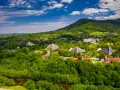 Ustroń otoczony zielonymi górami, z charakterystycznymi budynkami o trójkątnych dachach.