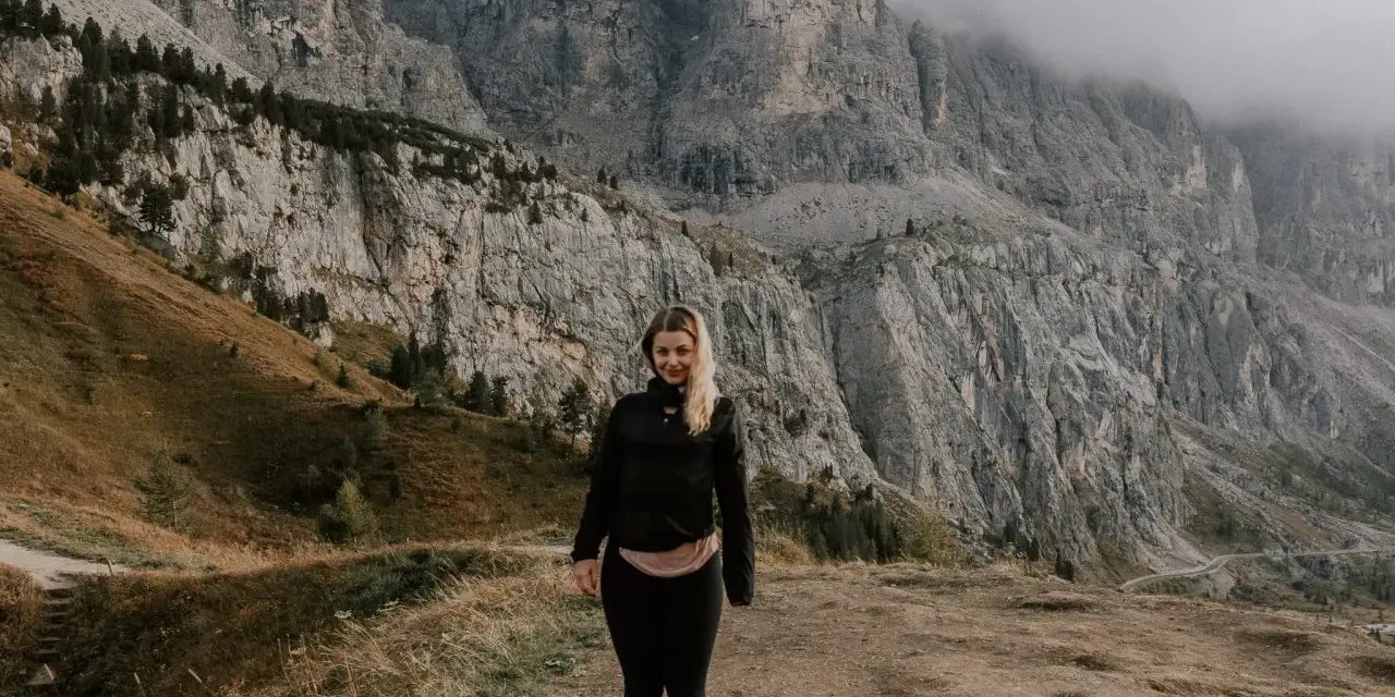 Kobieta na tle majestatycznych gór w Val di Funes. Mgła otula szczyty, tworząc mistyczną atmosferę.