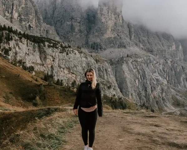 Kobieta na tle majestatycznych gór w Val di Funes. Mgła otula szczyty, tworząc mistyczną atmosferę.