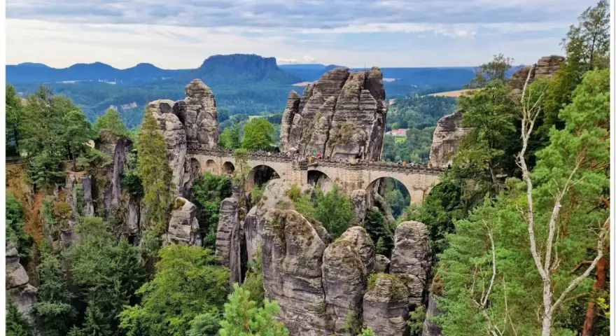 Kamienny most Basteibrücke w Szwajcarii Saksońskiej, łączący skalne baszty pośród zielonych lasów i gór.