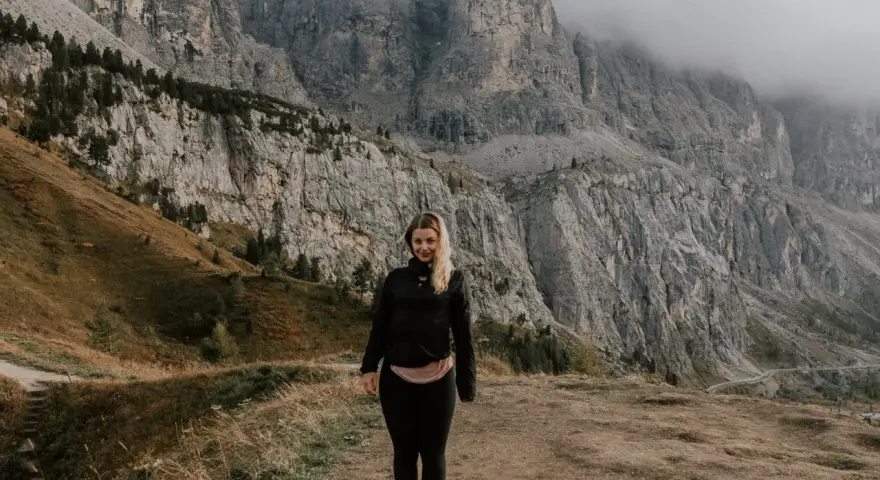 Kobieta na tle majestatycznych gór w Val di Funes. Mgła otula szczyty, tworząc mistyczną atmosferę.