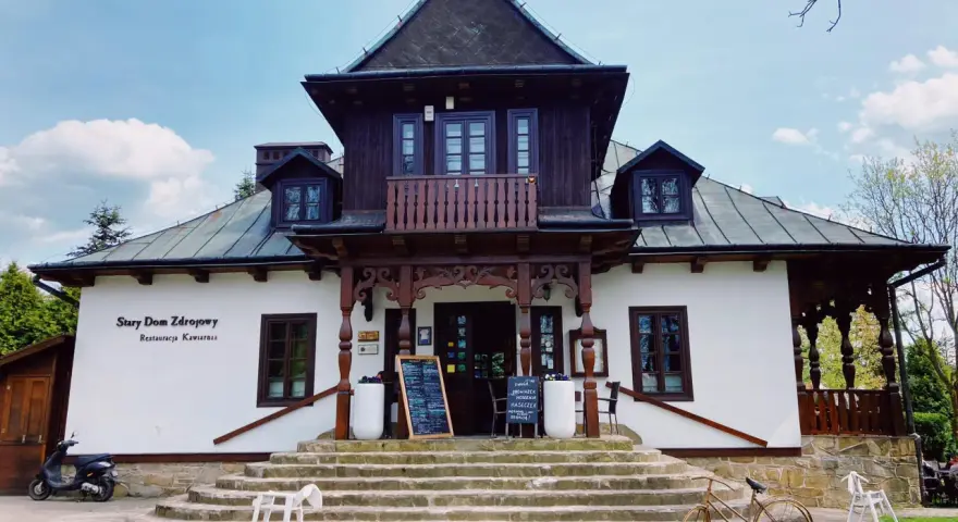 Stary Dom Zdrojowy w Beskidach, z charakterystyczną architekturą i kamiennymi schodami, zaprasza do restauracji.