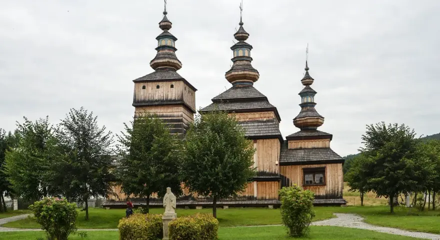 Drewniana cerkiew z trzema kopułami, otoczona zielenią. Wspaniałe krempna atrakcje dla miłośników historii i architektury.