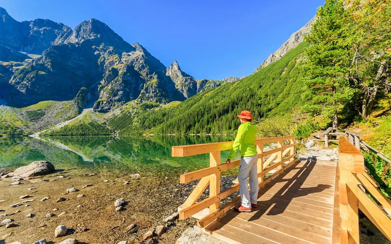 Idealne jednodniowe wycieczki w góry z Krakowa: turystka podziwia malownicze Tatry nad Morskim Okiem.